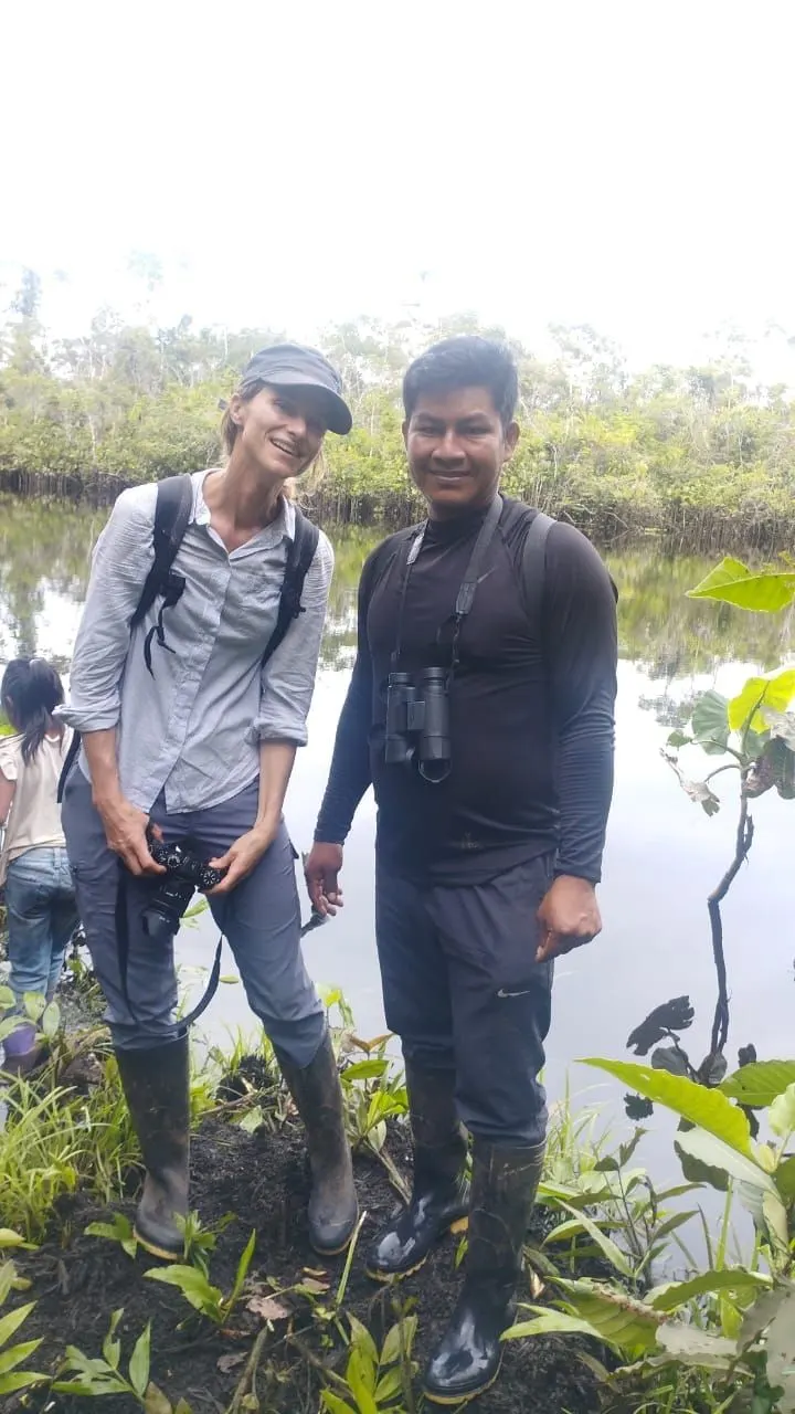 Guía de la comunidad acompañando a una visitante a orillas de una laguna del Yasuní