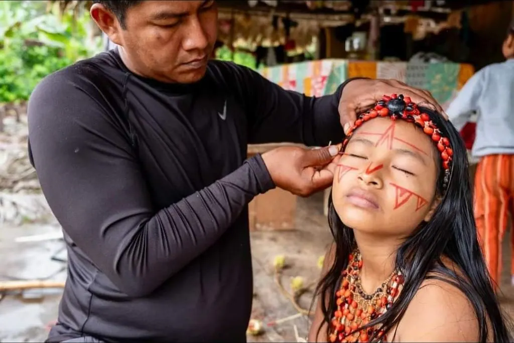 Un integrante de la comunidad kichwa pinta con achiote el rostro de una niña